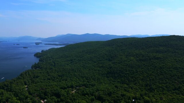 Islands of Lake George aerial drone Adirondack Mountains July Up State New York Town of Lake George landscape harbor view boats boating Assembly Point spring summer sunny morning blue sky forward left