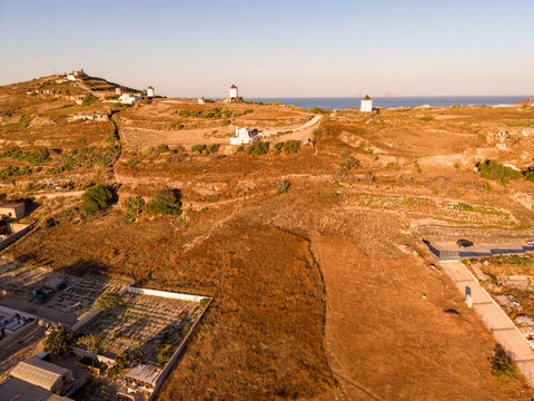 Wide aerial drone photo of historic windmills on Gavrilos Hill near Emporio in Santorini Greece at sunset