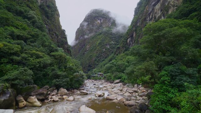 Amazon Urabumba river Machu Picchu Aguas Calientes dry rainy season misty clouds Peru jungle hillside Peruvian Andes Mountains lower highlands Inca trail citadel nature landscape pan left motion