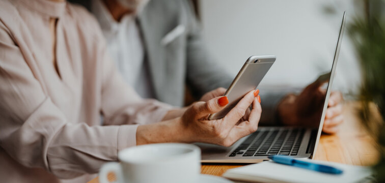 Close up of woman in coffe shop, holding smartphone and making reservation.
