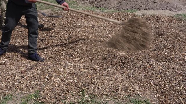Gardeners spreading water-retaining wood chip mulch to create a rain garden