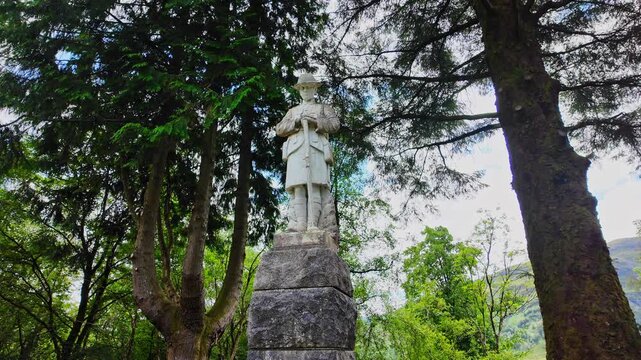 Low angle pan of the statue of a British Soldier in remembrance of the lives lost in World War 1 in the highlands of Scotland on a sunny, summer day