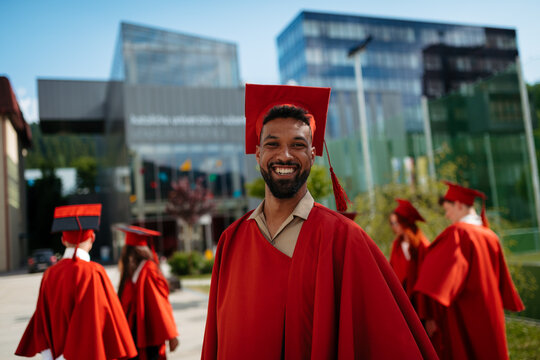 University student celebrating with classmates, looking at camera, graduation concept.