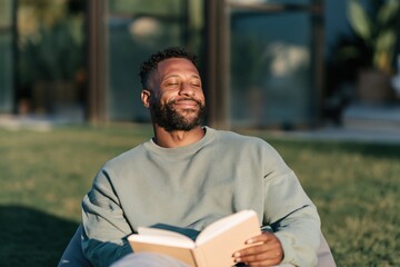 Fototapeta premium Relaxed man sunbathing outdoors with book portrait for lifestyle background and mindfulness banner design
