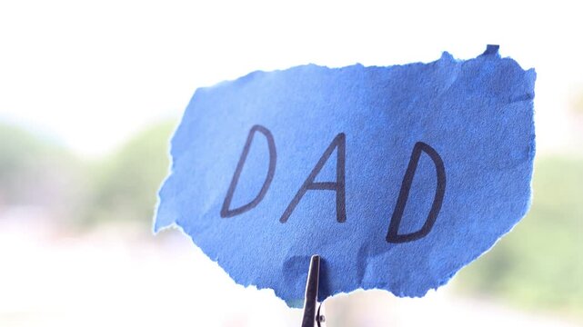 Una toma de cerca de un papel azul rasgado con la palabra padre movi&eacute;ndose con el viento  