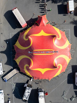 Kempele, Finland - 29 July 2026: Aerial view of Traveling Circus Tahti with its vibrant red and yellow big top tent in an asphalt lot, surrounded by support vehicles.