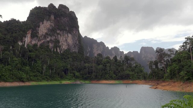Ratchaprapha Dam on a rainy day at khao sok national park, surat thani province thailand featuring spectacular limestone mountains shrouded in mist.