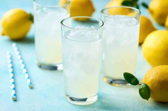 Glasses of freshly made lemonade on turquoise background, selective focus.