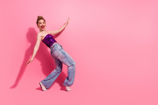 Fashionable woman posing in a vibrant outfit against a pink background, expressing joy and confidence with a stylish flair