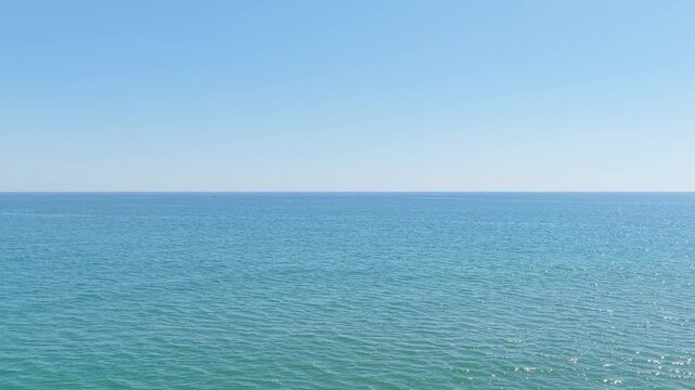 Wide shot of the tranquil Mediterranean Sea under a clear blue sky at Platja de Pals, Begur, Spain. The video captures gentle waves and the vast open water, with no people or boats visible.