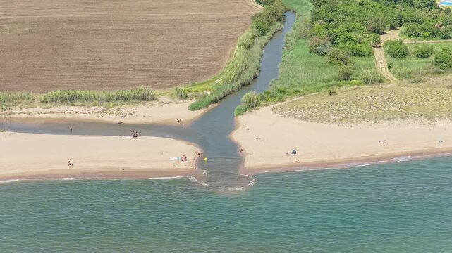 Aerial footage captures the river mouth meeting the Mediterranean Sea at Platja de Pals beach in Begur, Spain.