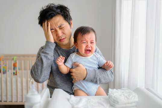 Exhausted and Stressed Asian father holding his crying baby at home, suffering from parenting alone, difficult childcare
