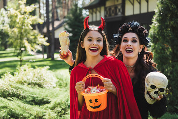 Fototapeta premium Mother and child share joyful moments in festive Halloween costumes outdoors