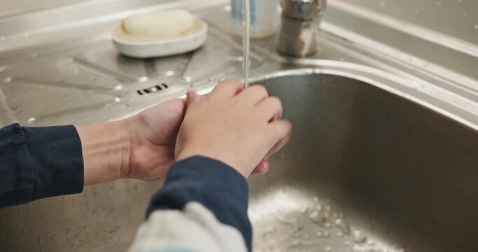 Kid hands wash peach under tap water in sink. Boy help in kitchen. 4K 10-bit