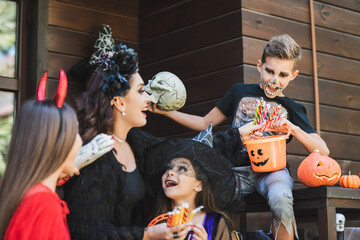 Fototapeta premium Family enjoying Halloween fun while trick or treating near a decorated cottage