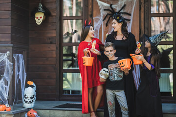 Fototapeta premium Family enjoying Halloween fun with costumes and treats at a cozy cottage