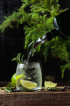 Gin is poured from the vintage bottle into a glass with ice and a lime wedges.