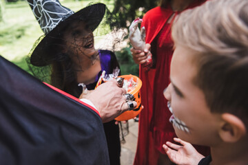 Fototapeta premium Family enjoying Halloween fun while trick or treating near a decorated cottage