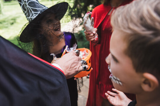 Family enjoying Halloween fun while trick or treating near a decorated cottage