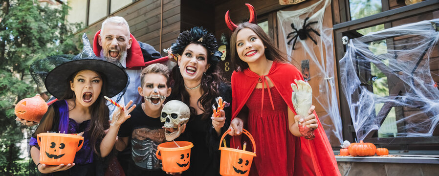 Joyful family celebrates Halloween in costumes while trick or treating outdoors