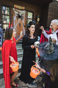 Happy family in costumes enjoying Halloween treats at a cottage