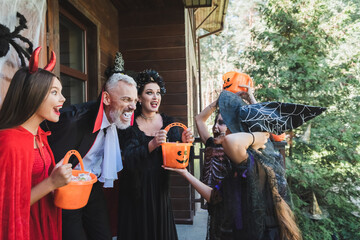 Fototapeta premium Joyful family celebrating Halloween together with costumes and treats