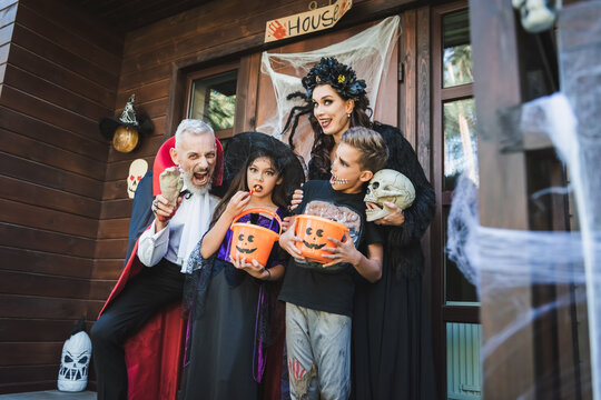 Family enjoying Halloween festivities near a spooky decorated cottage house
