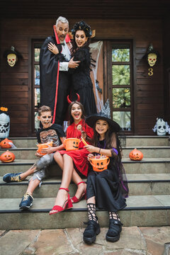 Happy family enjoying Halloween fun in costumes on a decorated porch