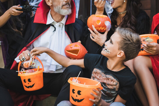 Joyful family enjoying Halloween traditions in spooky costumes outdoors