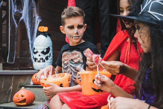 Families trick-or-treating at a cozy, decorated cottage this Halloween