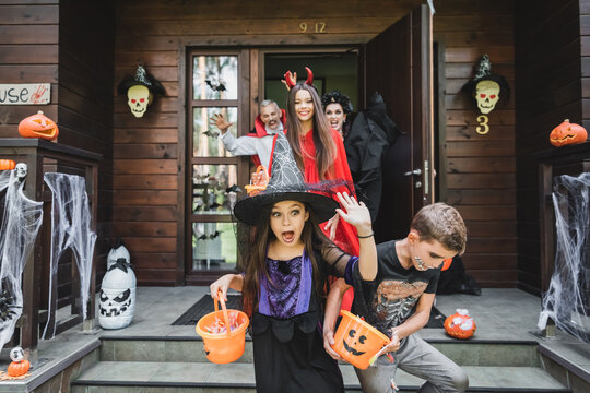 Joyful family celebrates Halloween with costumes and treats at a spooky cottage