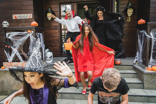 Happy family enjoying Halloween fun at a decorated cottage with costumes