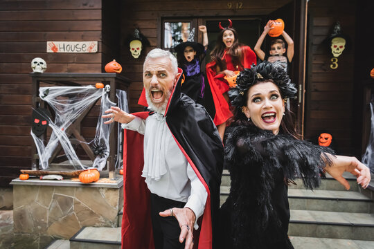 Fun family trick or treating in Halloween costumes at a decorated cottage