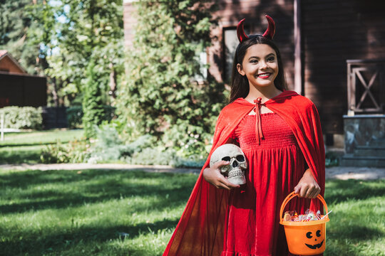 Cute kid dressed as a devil enjoying Halloween at a decorated house