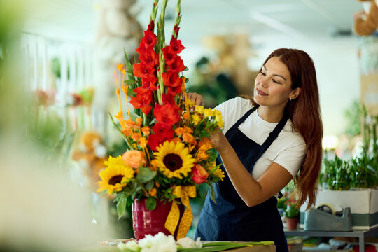 Florist Woman Arranging Bright Sunflower And Gladiolus Bouquet In Small Flower Shop While Wearing Apron