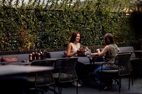 Two Friends Chatting Over Drinks at an Outdoor Cafe Terrace for Casual Urban Relaxation
