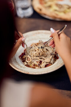 Woman Twirling Creamy Pasta With Forks at Rustic Restaurant Table &mdash; Casual Dining, Food Blog Image