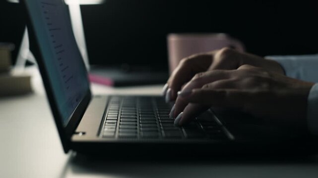 Female hands typing on laptop keyboard with camera sliding left close up