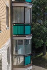 Enclosed glazed balcony with green panels on the facade of a residential apartment building....