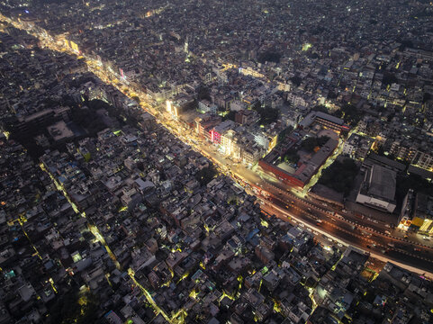 Aerial view of the dense urban landscape of New Delhi at night, featuring illuminated streets, bustling traffic, and closely packed buildings in New Delhi, Delhi, India.