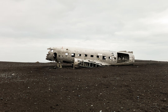 An abandoned crashed airplane fuselage on a black sand desert