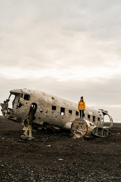 A white woman stands on an abandoned crashed airplane fuselage