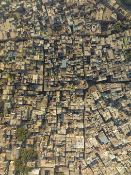 Aerial view of the dense urban fabric of Old Delhi, featuring a complex network of narrow streets, closely packed residential rooftops, and historic buildings in New Delhi, Delhi, India.
