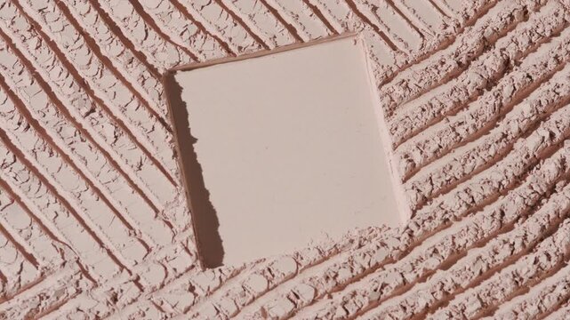 Vertical jib shot of beige powder furrows surface lit by moving directional light casting dynamic shadows