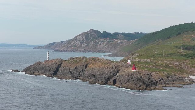 Aerial view of the rugged coastline near Cangas, Spain, featuring the iconic Faro de Cabo Home and Faro de Punta Robaleira lighthouses. No people are visible in the natural landscape.