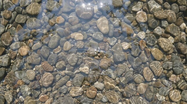 Top view of smooth stones submerged in crystal clear rippling water. Perfect for spa websites, wellness blogs, and meditation and relaxation content.