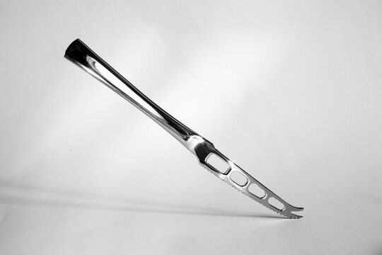 shiny stainless steel chesse knife on white background, kitchen utensils,cutlery,food and drink concept, free copy space, black and white image.