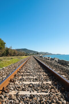 Prospettiva centrale di binari ferroviari arrugginiti sul Mar Ionio a Palizzi