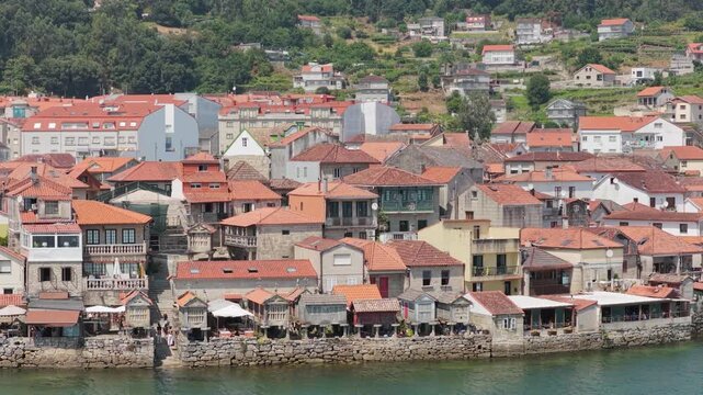 A scenic view of the historic coastal village of Combarro in Spain, featuring traditional stone houses with red tiled roofs clustered along the waterfront.