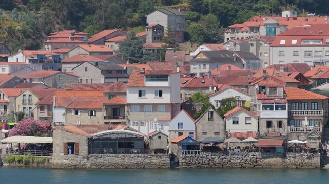 A detailed view of the picturesque waterfront village of Combarro, Spain, featuring traditional stone houses with red tile roofs clustered along the shoreline.